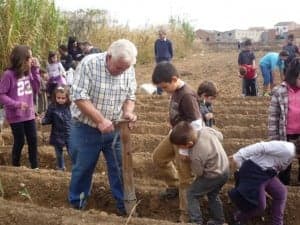 Un abuelo enseña a los alumnos a trabajar el huerto. 