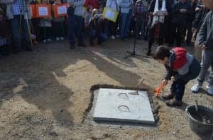 Un niño echa cemento sobre la primera piedra. JLP.
