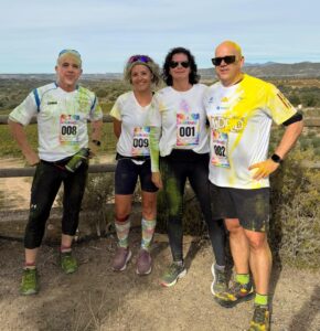 Cuatro participantes con dorsales y camisetas cubiertas de colores posan durante la carrera de Experiencias Somontano en Viñas del Vero.